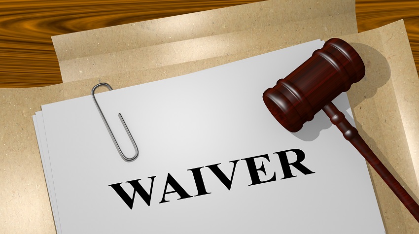 The word "waiver" in black on a white piece of paper, with a gavel and paperclip.