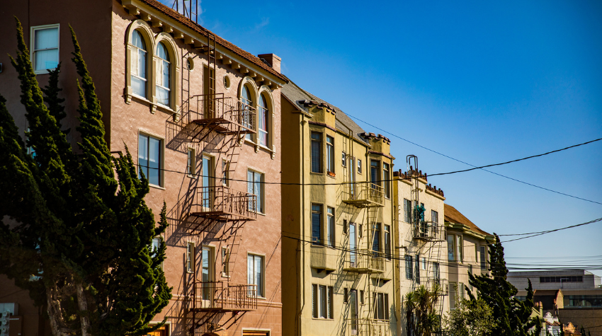 Facades of four apartment buildings in Berkeley set against a blue sky,